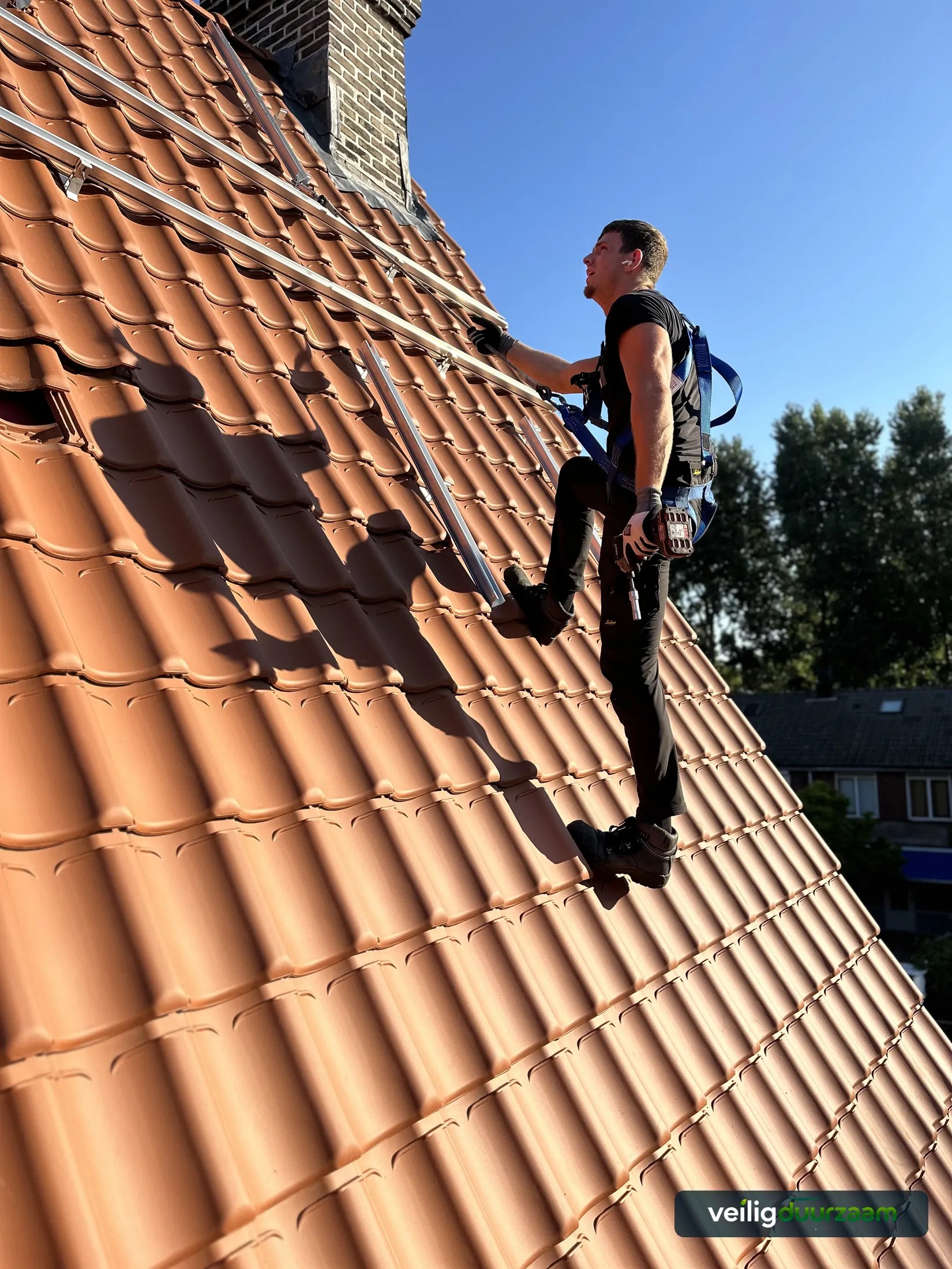 Monteur werkt met valbeveiliging aan zonnepanelen in Haarlem