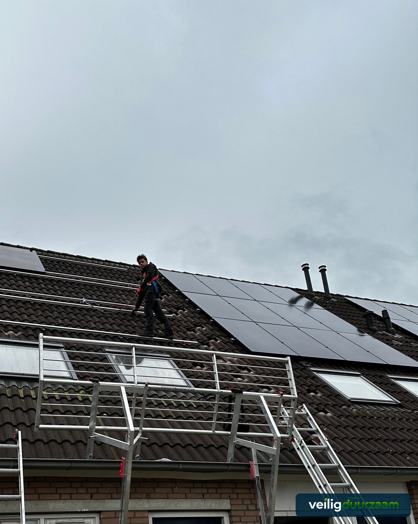 Monteur werkt achter RSS-dakrandbeveiliging aan zonnepanelen in Numansdorp